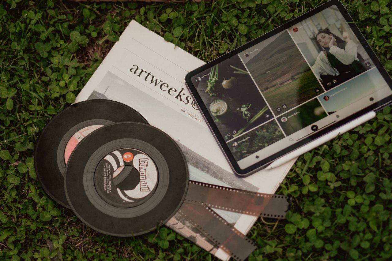 why-choose-us A flat lay of vintage films, a newspaper, and a tablet on grass.
